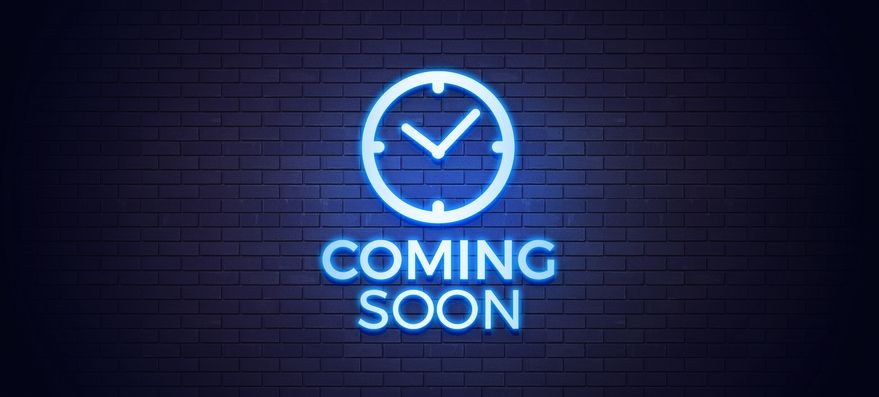 Neon blue 'Coming Soon' sign with a clock icon on a dark brick wall.